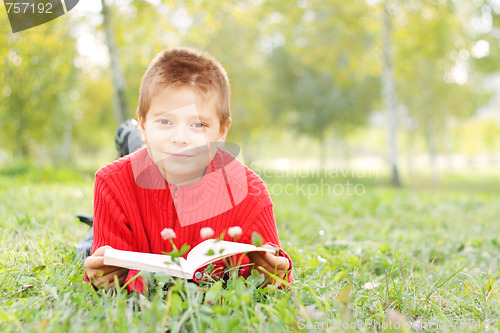 Image of Boy with book laying on grass