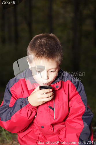 Image of Boy with hot drink in dark forest