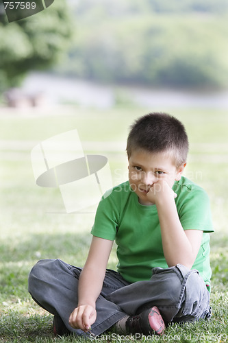Image of Boy in casual on grass leaning on fist