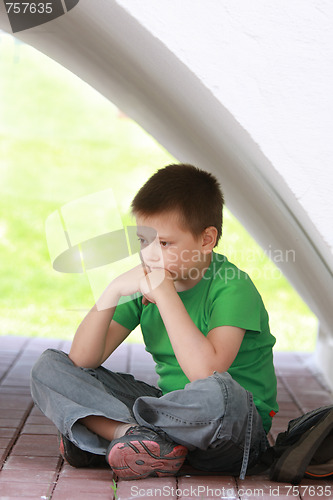 Image of Pensive boy in green under wall