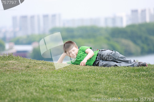 Image of Boy in casual laying down on grass