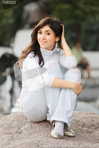 Image of Girl in casual sitting on stone