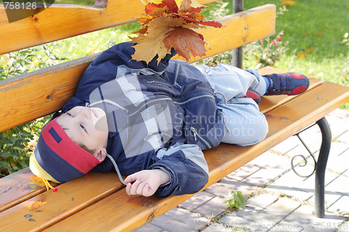 Image of Little boy laying on bench