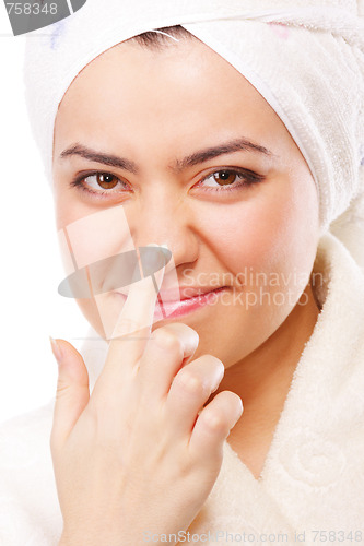 Image of Smiling woman in bathrobe applying moisturizer