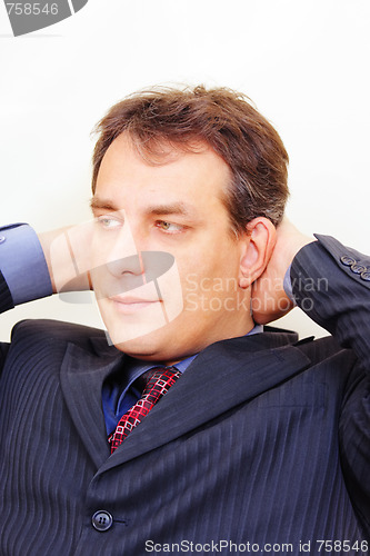 Image of Serious businessman with hands behind head