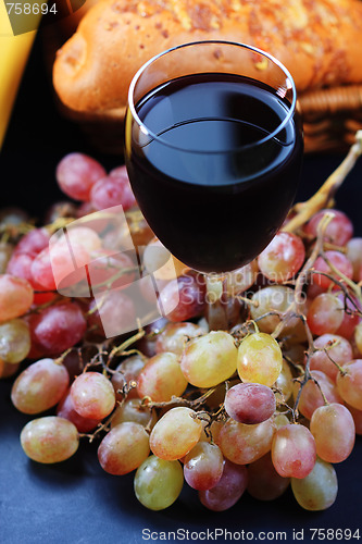 Image of Glass of red wine covered with grapes