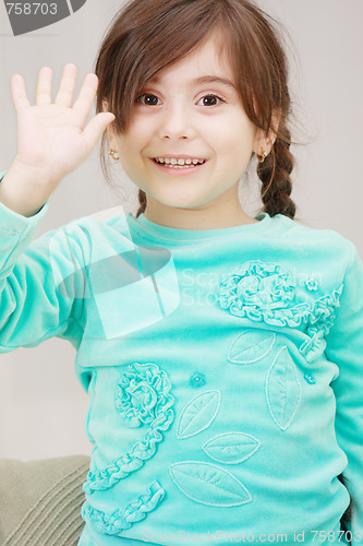 Image of Little girl raises hand in greeting
