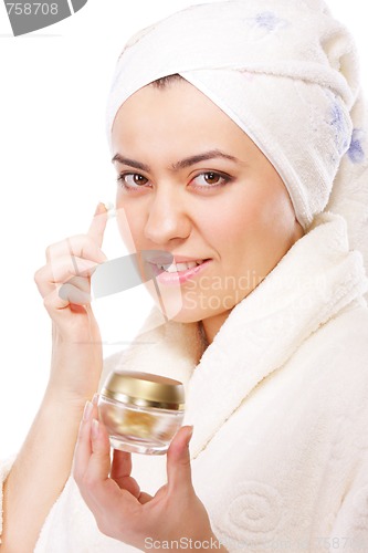 Image of Woman in bathrobe applying moisturizer