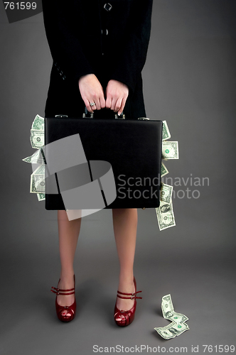 Image of Woman holding briefcase overflowing with money