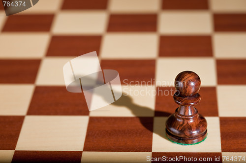 Image of Chess piece - a black pawn on a chessboard.