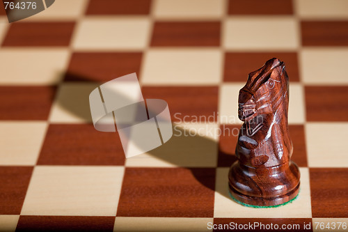 Image of Chess piece - a black knight on a chessboard.