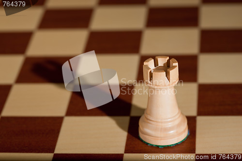 Image of Chess piece - a white rook on a chessboard.