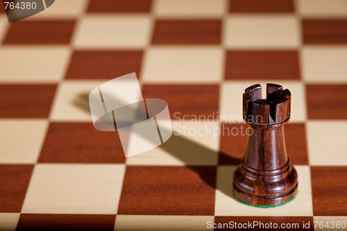 Image of Chess piece - a black rook on a chessboard.