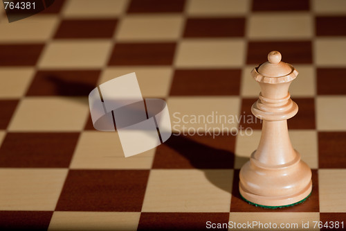 Image of Chess piece - a white queen on a chessboard.