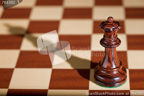 Image of Chess piece - a black queen on a chessboard.