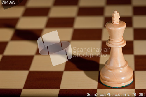 Image of Chess piece - a white king on a chessboard.