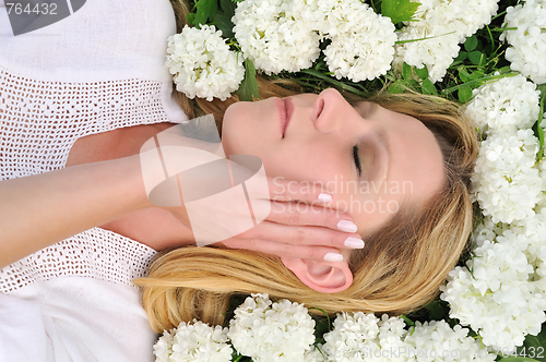 Image of Young woman laying in flowers - snowballs