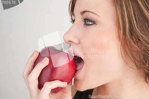 Image of Beautiful girl biting red apple