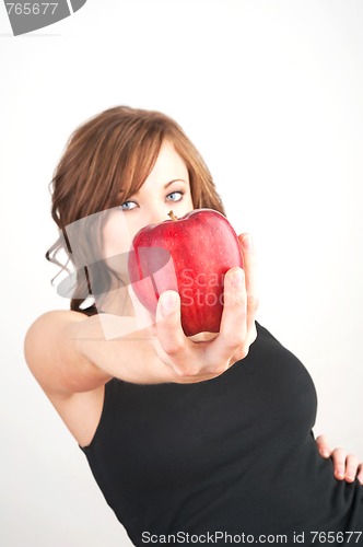 Image of Beautiful girl holding a red apple, extended toward camera