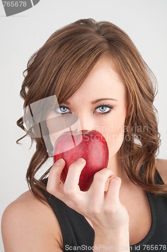 Image of Beautiful girl holding an apple in front of her face