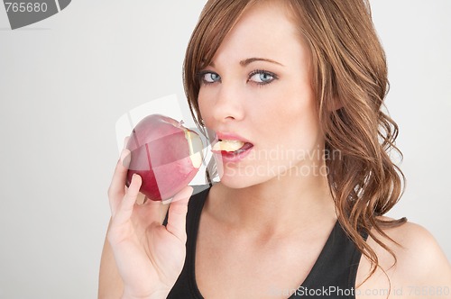 Image of Beautiful girl biting off a piece of a red apple