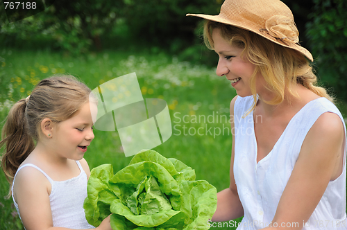 Image of Young mother and daughter with lettuce