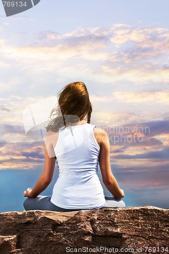 Image of Young girl meditating at sunset