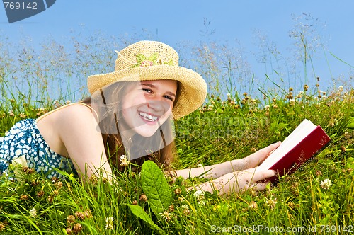 Image of Young girl reading book in meadow