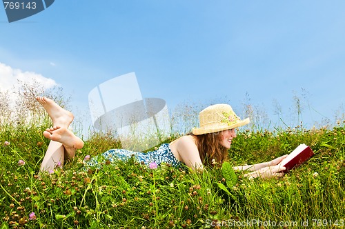 Image of Young girl reading book in meadow