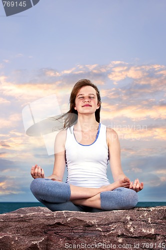 Image of Young girl meditating at sunset