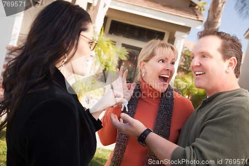 Image of Hispanic Female Real Estate Agent Handing Keys to Excited Couple