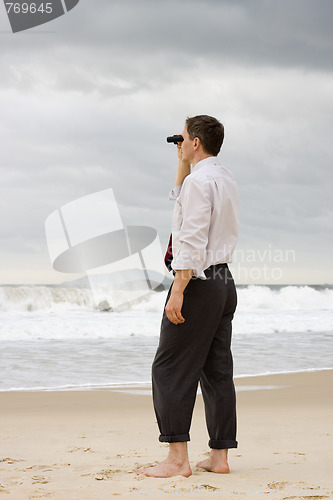 Image of Businessman on a beach searching with binoculars