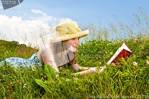 Image of Young girl reading book in meadow