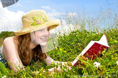 Image of Young girl reading book in meadow