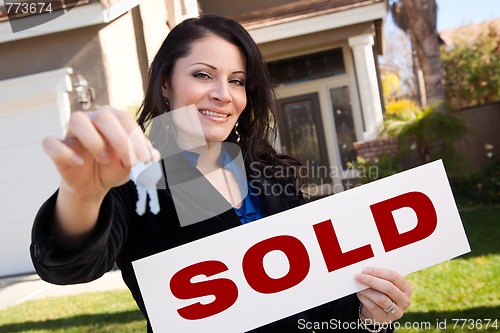 Image of Hispanic Woman Holding Keys and Sold Sign In Front of House