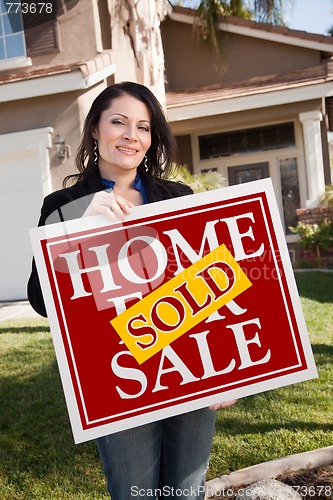 Image of Hispanic Woman Holding Red Sold Real Estate Sign In Front of Hou