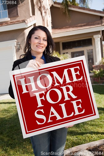 Image of Hispanic Woman Holding Real Estate Sign In Front of House