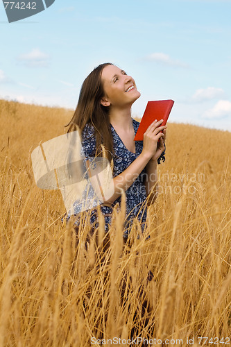 Image of woman with a book in cereals field 