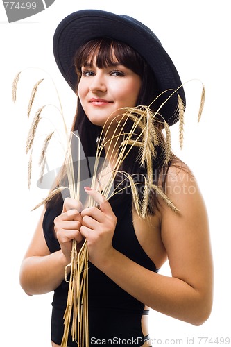 Image of woman with bunch of wheat in blue hat smile