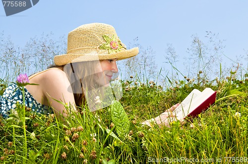 Image of Young girl reading book in meadow