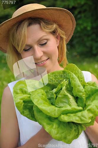Image of Young woman holding fresh lettuce