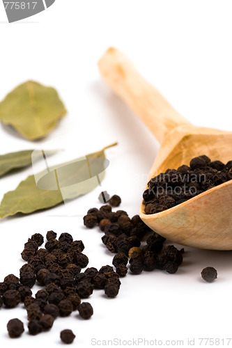 Image of black pepper on wooden spoon and bay leaves