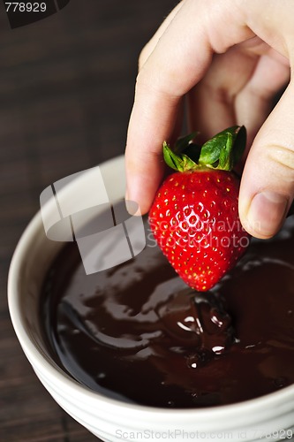 Image of Hand dipping strawberry in chocolate