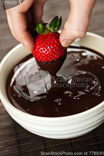 Image of Hand dipping strawberry in chocolate