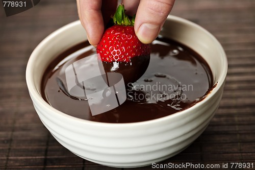 Image of Hand dipping strawberry in chocolate