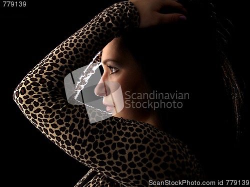 Image of Young brunette on black profile touching hair