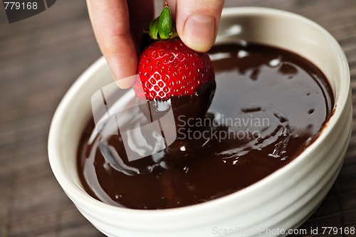 Image of Hand dipping strawberry in chocolate