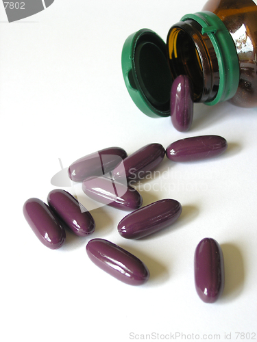 Image of Big purple pills spilling from brown bottle.