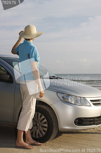 Image of Woman standing beside a car on a beach