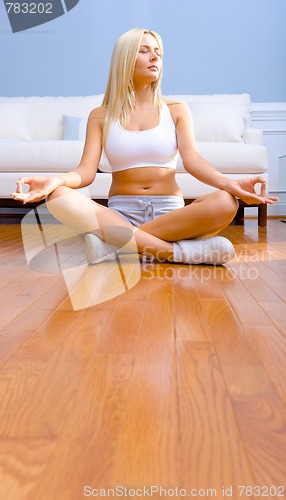 Image of Young Woman Sitting on Wood Floor Meditating